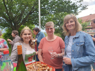 Weinkönigin mit zwei Frauen an Stehtisch mit Weingläsern und Brezen