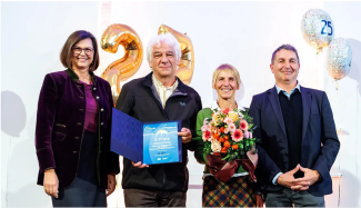 vier Personen mit Urkunde und Blumenstrauß