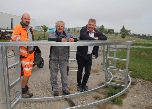 Drei Männer neben Metallgestell