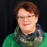 Frau mit grünem Pullover und blau-grünem Schal